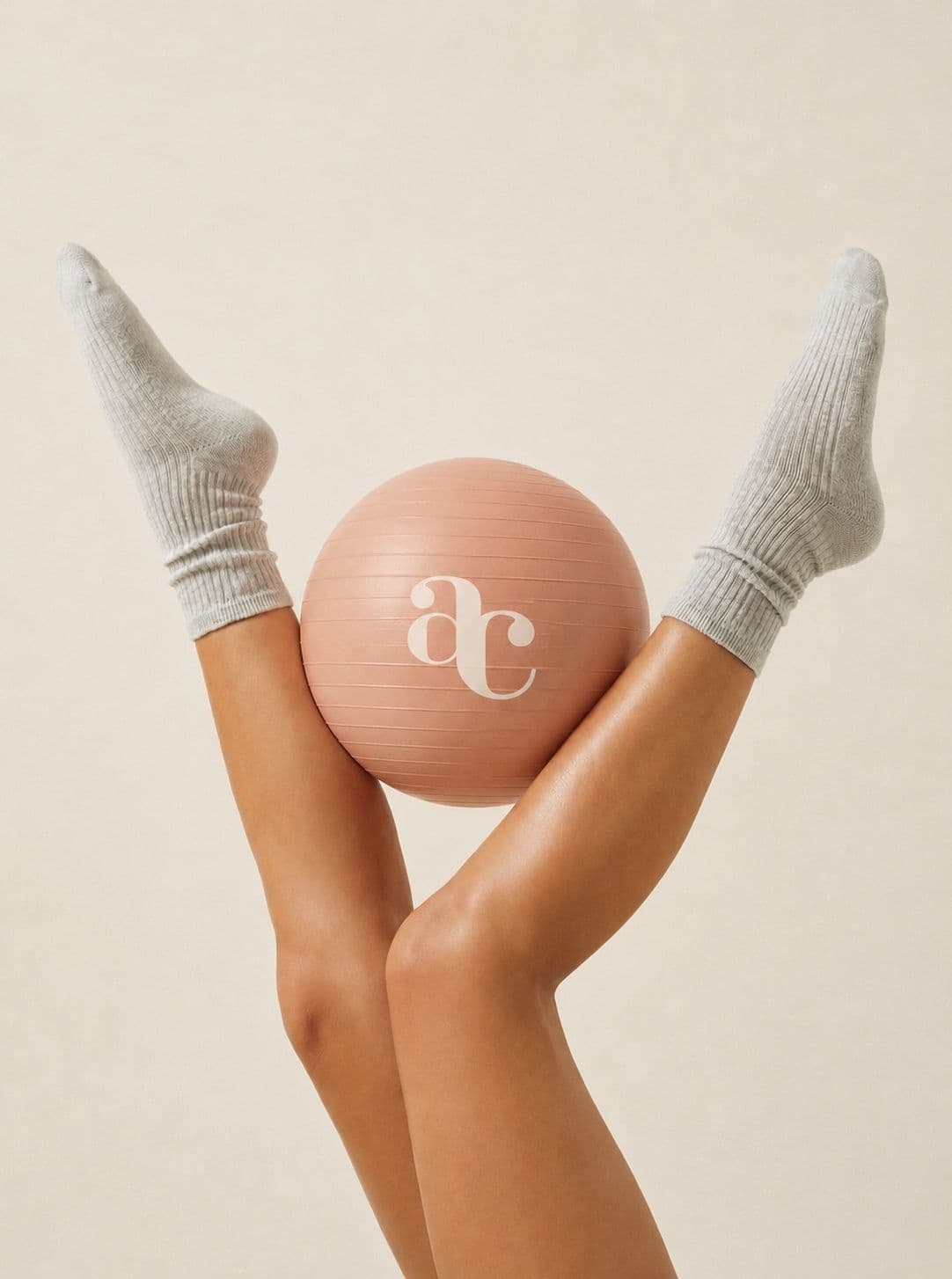 Piernas sosteniendo una pelota de pilates con el logo de Andrea Carrió Studio